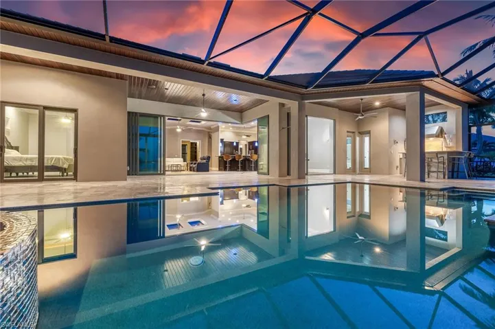 Pool at dusk featuring a ceiling fan, a patio, a lanai, and a pool