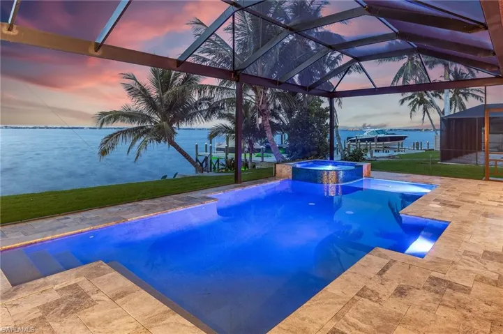 View of swimming pool with a patio area, a lanai, a pool with connected hot tub, and a lawn