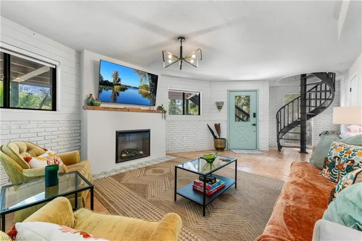 Tiled living room featuring an inviting chandelier and brick wall
