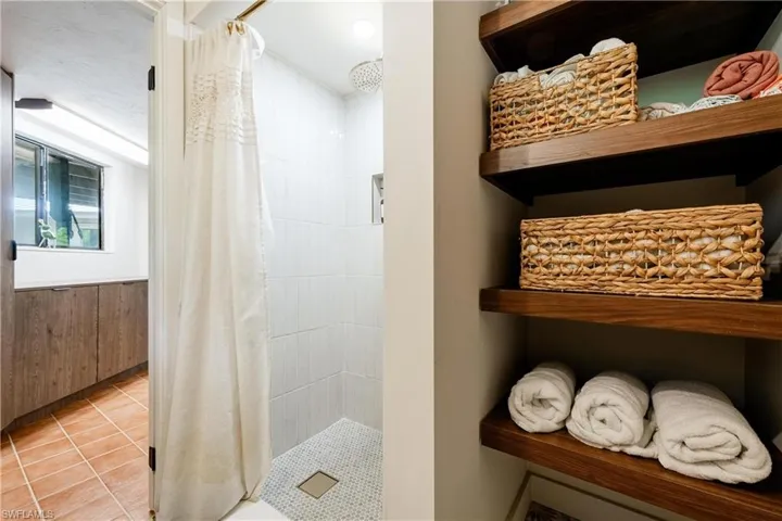 Bathroom featuring tile patterned flooring, wood walls, a shower with curtain, and a textured ceiling