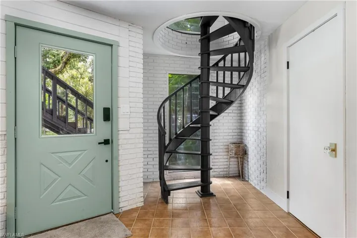 Entryway with tile patterned flooring and brick wall