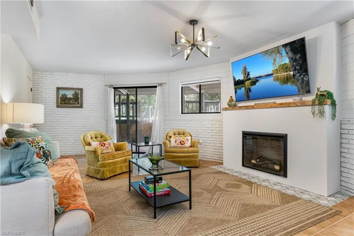 Living room featuring hardwood / wood-style floors, a chandelier, and brick wall