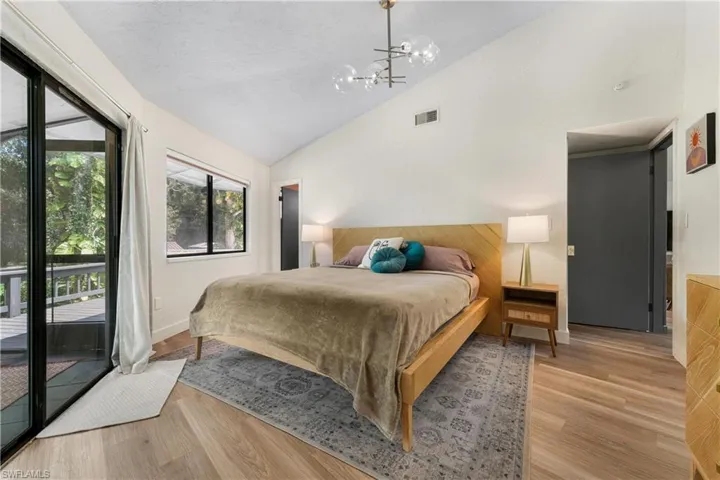 Bedroom with an inviting chandelier, high vaulted ceiling, access to exterior, and light hardwood / wood-style floors