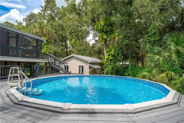 View of swimming pool featuring a wooden deck, an outdoor structure, and a sunroom