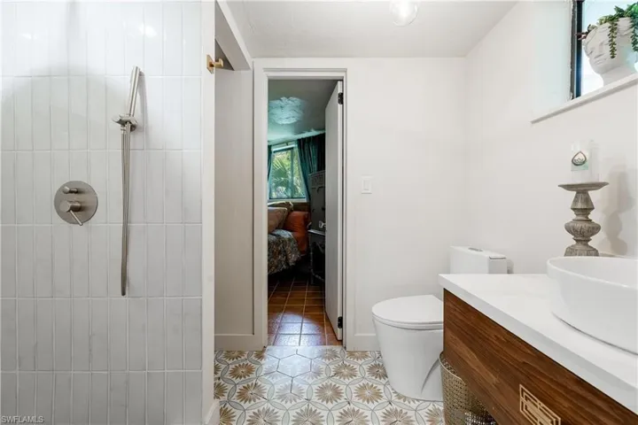 Bathroom featuring vanity, toilet, a wealth of natural light, and tiled shower
