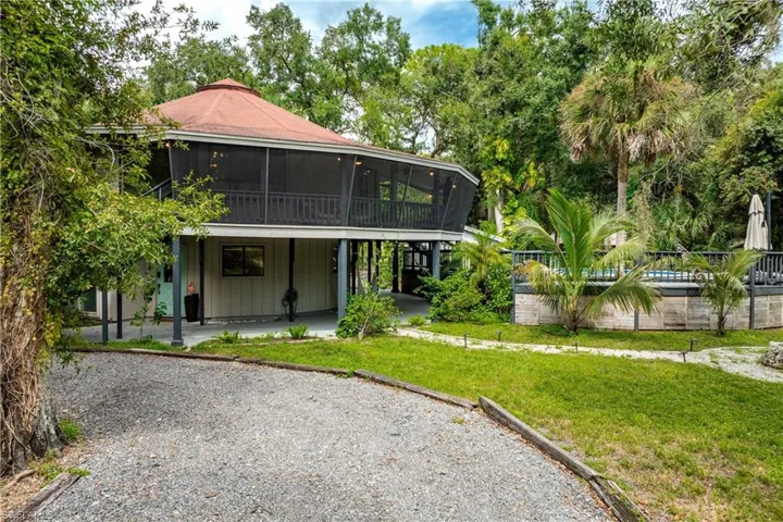 Rear view of property with a yard, a patio, a sunroom, and a swimming pool