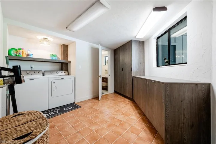 Laundry room featuring separate washer and dryer, a textured ceiling, and light tile patterned flooring