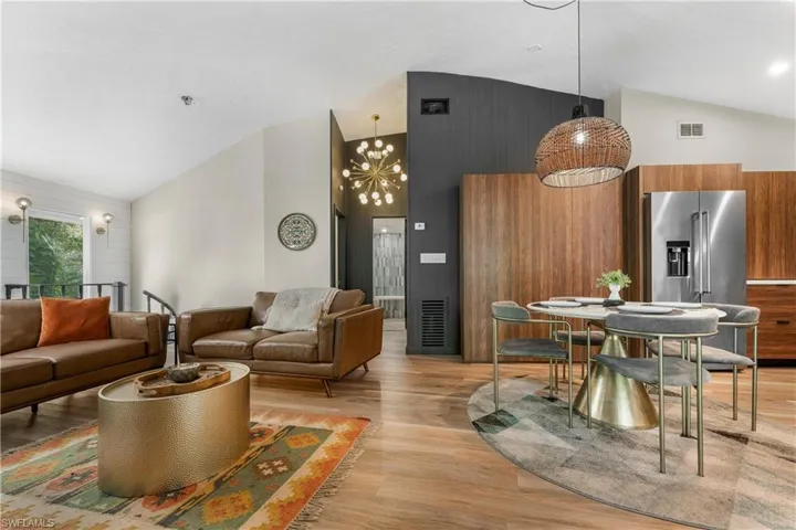Living room with high vaulted ceiling, a notable chandelier, and light hardwood / wood-style flooring