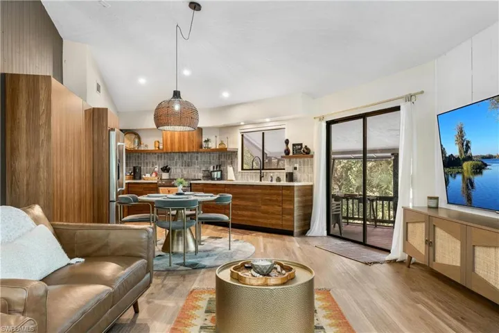 Living room featuring lofted ceiling, light hardwood / wood-style flooring, and sink
