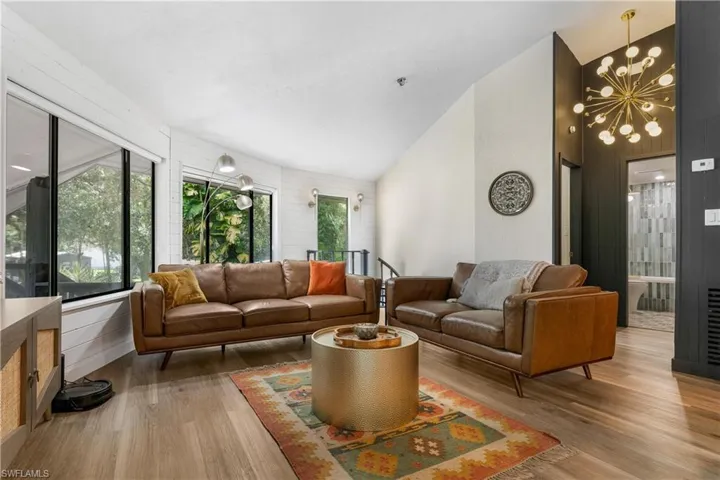 Living room with hardwood / wood-style flooring, high vaulted ceiling, a chandelier, and wooden walls