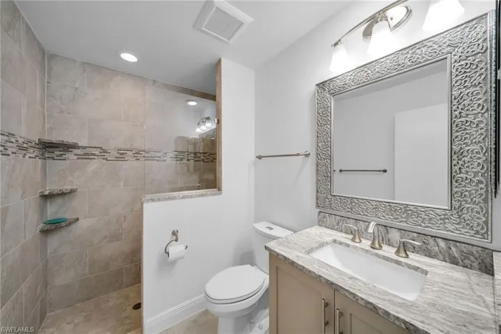 Bathroom with tile patterned floors, toilet, a tile shower, and vanity
