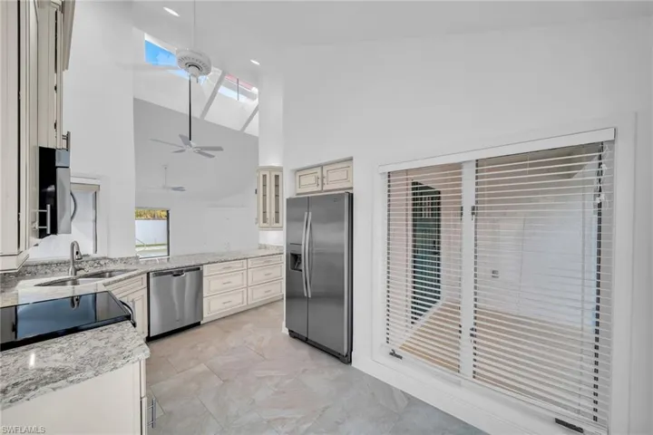 Kitchen with appliances with stainless steel finishes, sink, high vaulted ceiling, a skylight, and ceiling fan