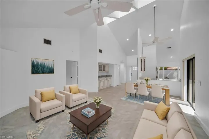 Living room featuring high vaulted ceiling, a skylight, and ceiling fan
