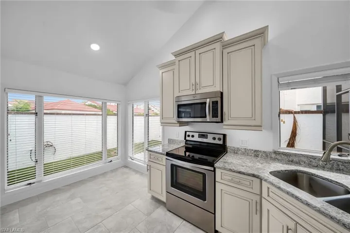 Kitchen featuring lofted ceiling, stainless steel appliances, cream cabinets, and sink