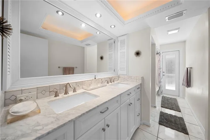 Bathroom featuring double vanity, a raised ceiling, shower / bath combo, tile flooring, and recessed lighting. Additionally, door to pool area