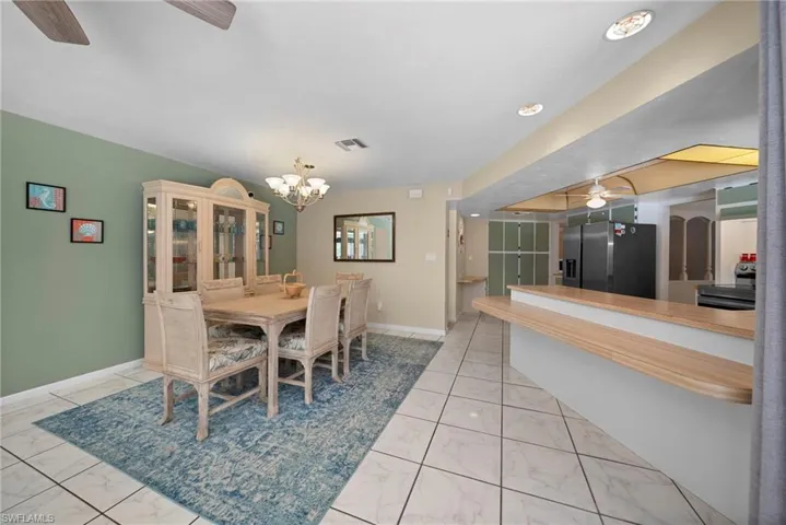 Dining area featuring a chandelier and tile floors. Kitchen bar