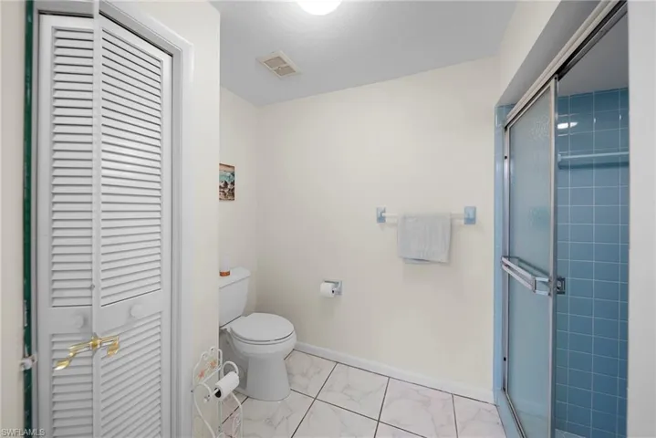 Ensuite bathroom with walk-in shower, tile flooring, and a closet