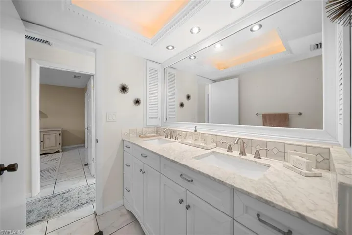 Bathroom featuring double vanity, tile floors, a tray ceiling, and recessed lighting