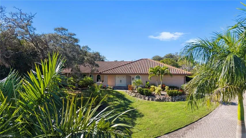 Mediterranean / spanish house featuring a high and dry lot, long paver driveway, front lawn, a tiled roof, and stucco siding