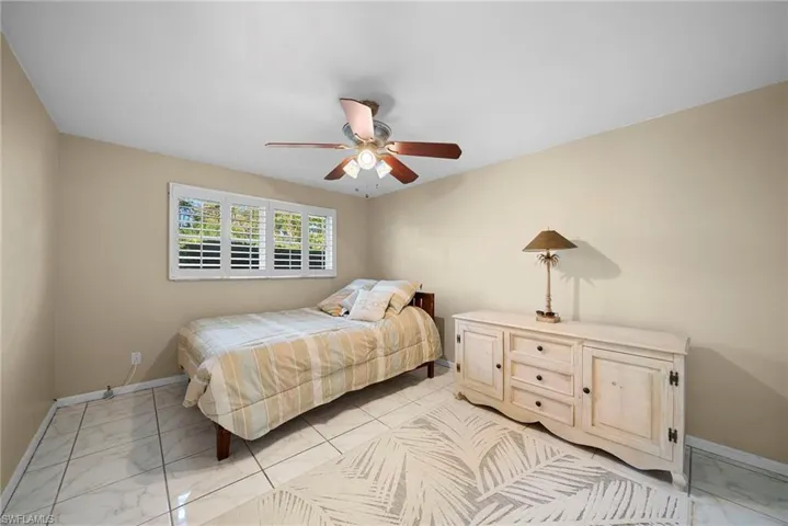 Bedroom with tile floors, ceiling fan and custom treatments