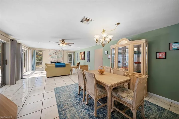 Dining area with ceiling fan, a chandelier, and a fireplace