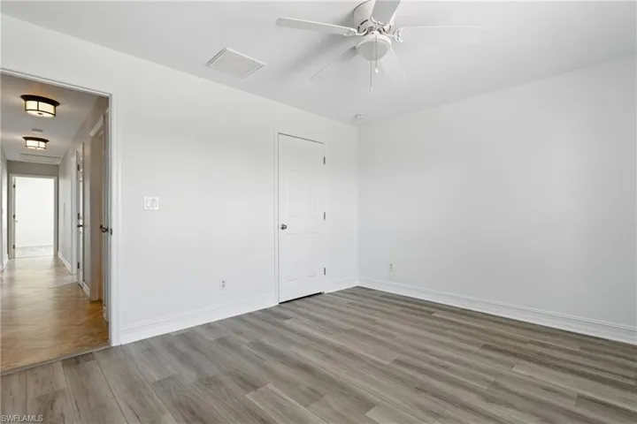 Empty room with baseboards, a ceiling fan, wood finished floors, and visible vents