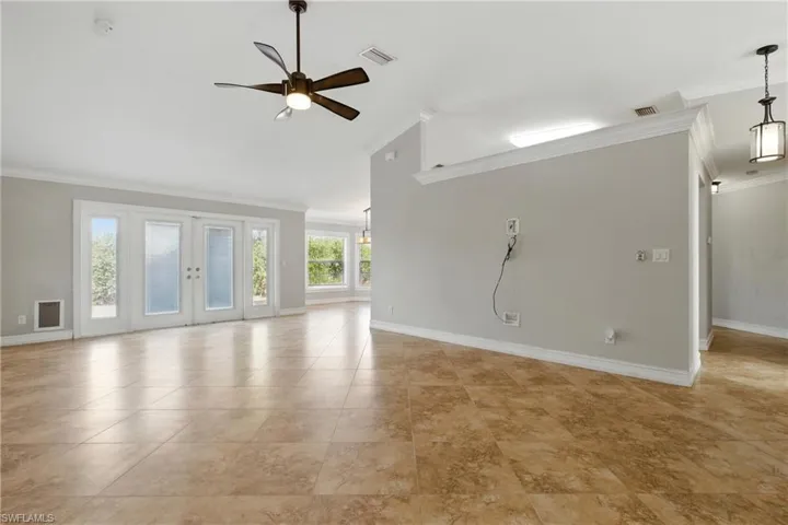 Unfurnished living room featuring a ceiling fan, baseboards, ornamental molding, and lofted ceiling