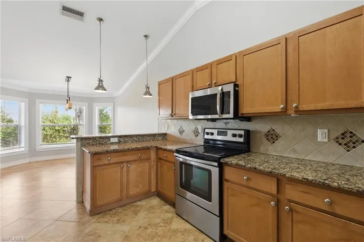 Kitchen featuring crown molding, stainless steel appliances, a peninsula, vaulted ceiling, and visible vents