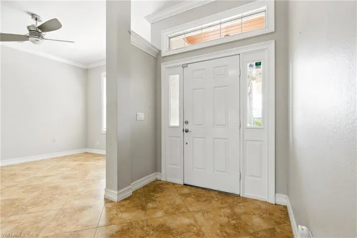 Foyer entrance with crown molding, baseboards, and a wealth of natural light