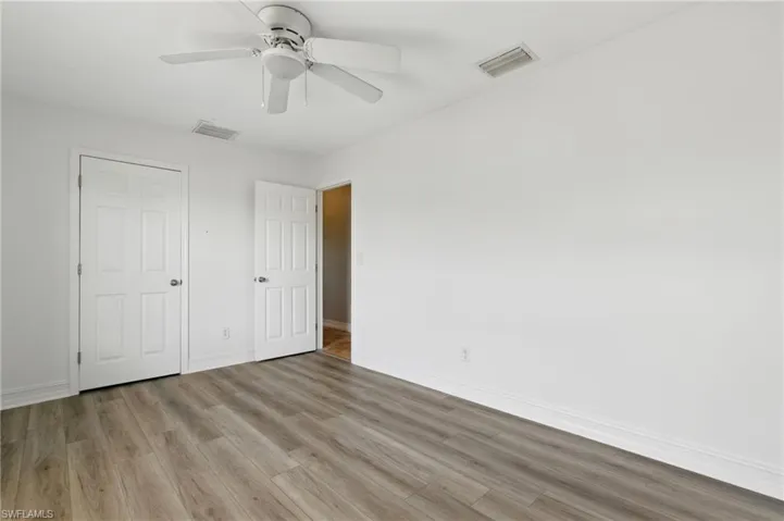 Unfurnished bedroom featuring baseboards, wood finished floors, and visible vents