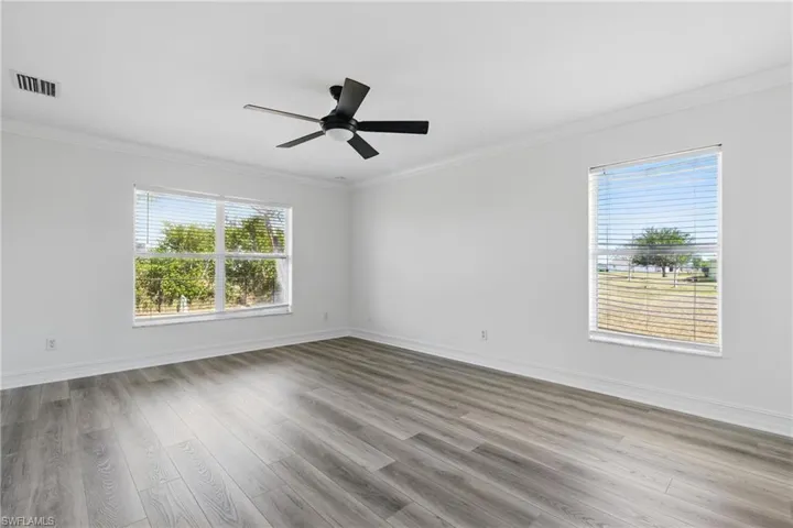 Unfurnished room with baseboards, ornamental molding, wood finished floors, and visible vents