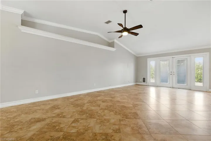 Unfurnished room with ceiling fan, visible vents, vaulted ceiling, baseboards, and ornamental molding
