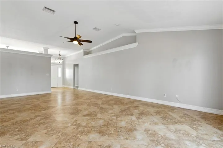 Empty room featuring crown molding, ceiling fan, and visible vents