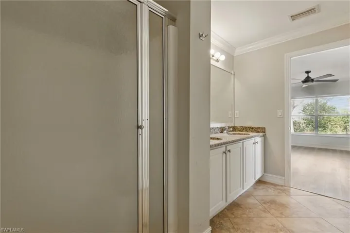 Full bath with crown molding, ceiling fan, a sink, a shower stall, and visible vents