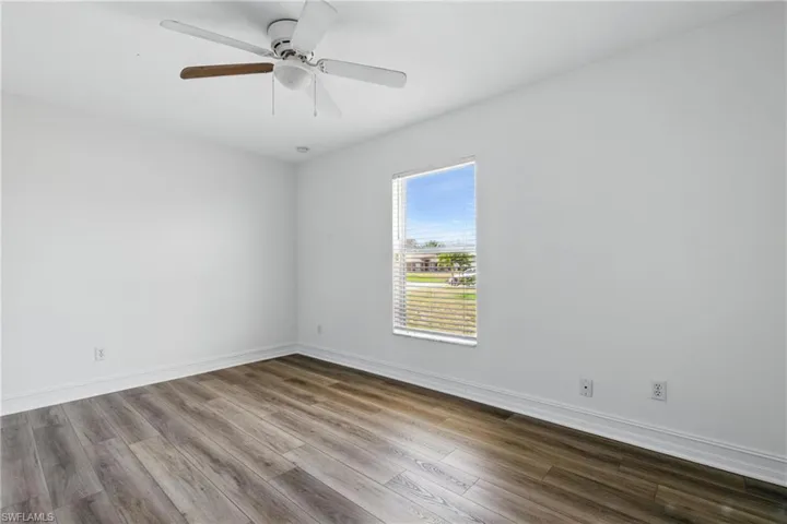 Empty room featuring baseboards, ceiling fan, and dark wood-style flooring