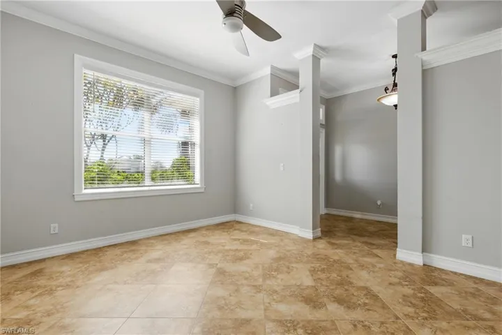 Empty room with a healthy amount of sunlight, baseboards, crown molding, and a ceiling fan