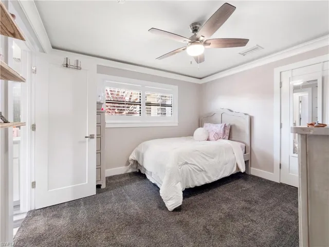 Carpeted bedroom with crown molding and a ceiling fan