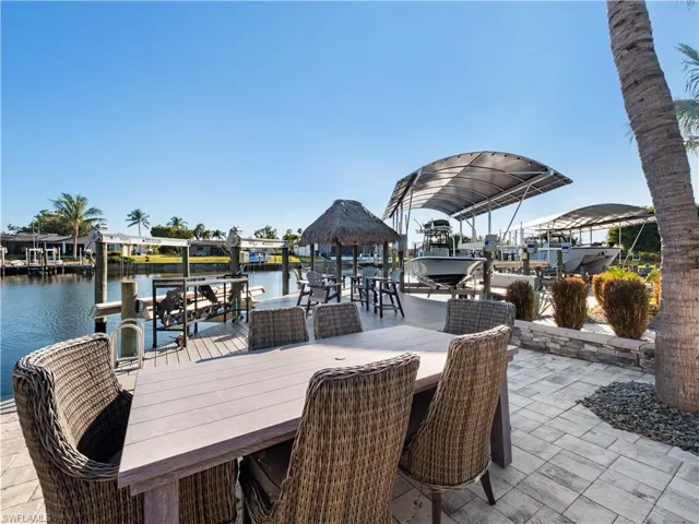 View of patio / terrace featuring boat lift, a boat dock, a water view, and outdoor dining area