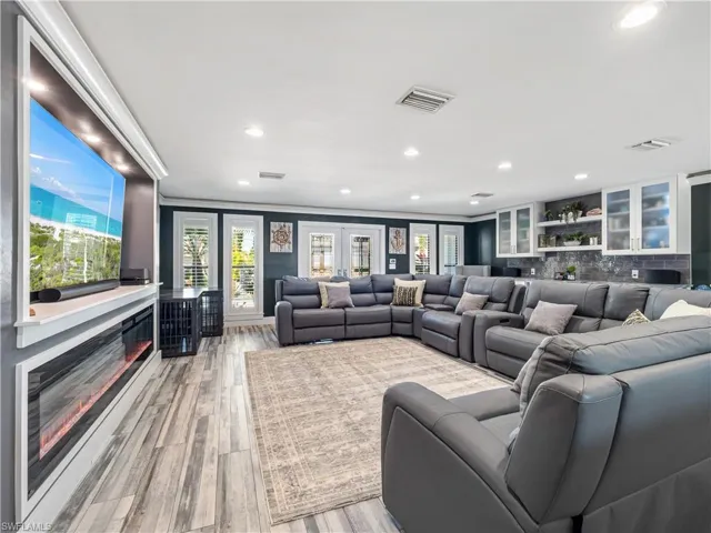 Cinema room with recessed lighting, wood finished floors, and a glass covered fireplace