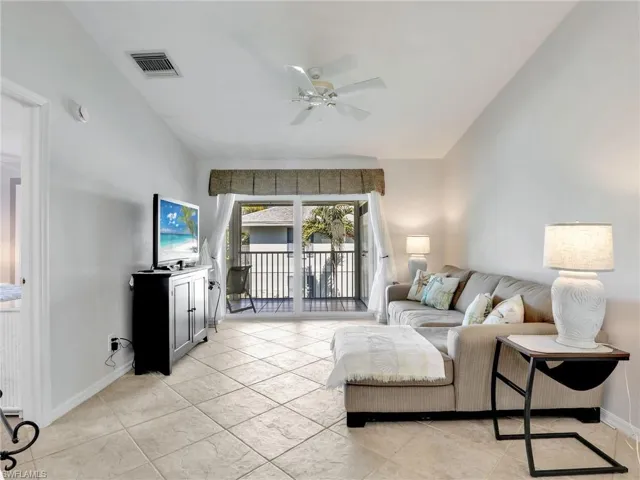 Living area with baseboards, visible vents, a ceiling fan, and lofted ceiling
