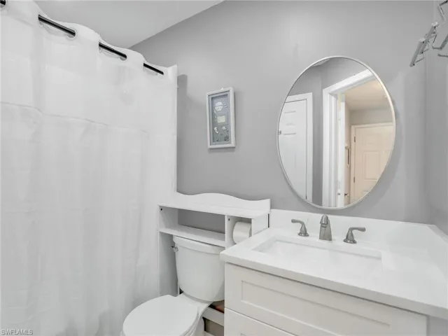 Bathroom featuring vanity, curtained shower, and toilet