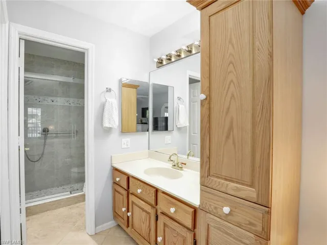 Bathroom with baseboards, a stall shower, vanity, and tile patterned flooring
