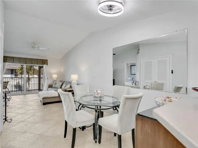 Dining area with lofted ceiling, light tile patterned floors, and a ceiling fan
