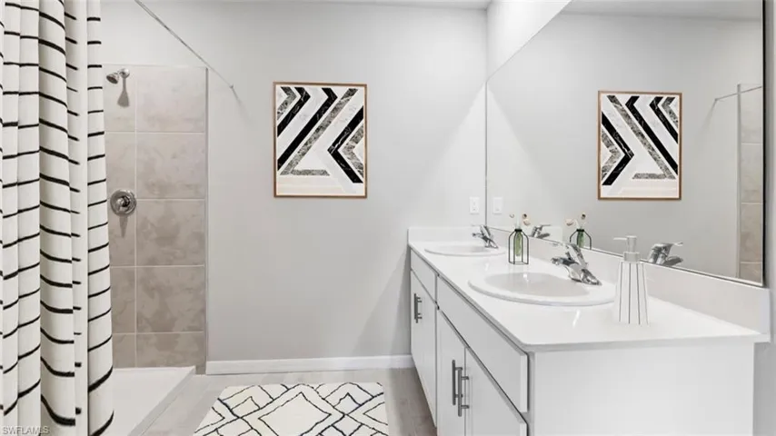 This image is virtually staged. Full bathroom with double vanity and a shower stall