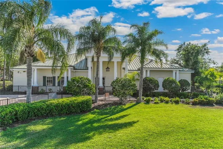 The property features a light-colored exterior with a green roof, complemented by a well-maintained lawn and lush landscaping