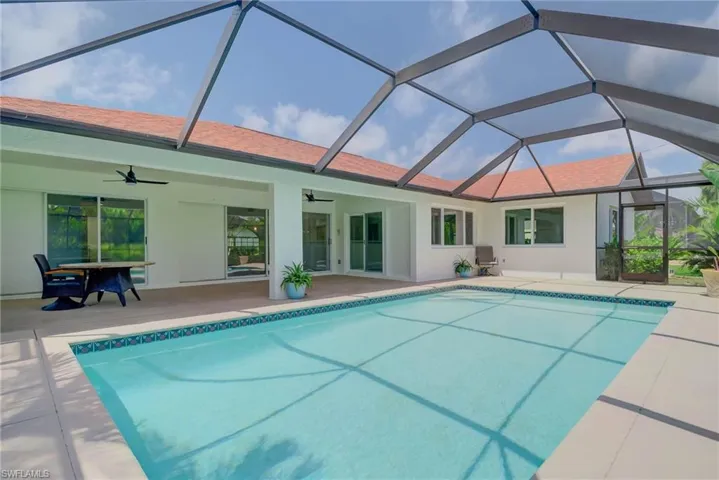 Outdoor pool featuring a ceiling fan, a patio area, and glass enclosure