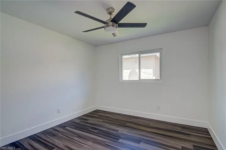 Spare room featuring baseboards, dark wood-style flooring, and ceiling fan