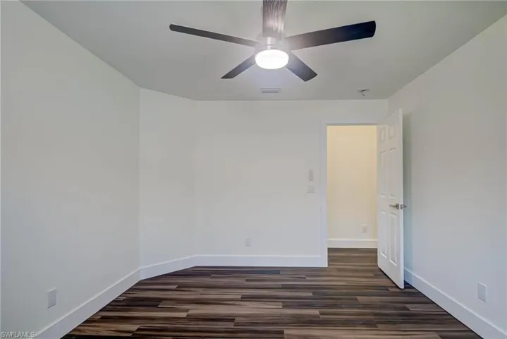 Spare room with dark wood finished floors, baseboards, and ceiling fan