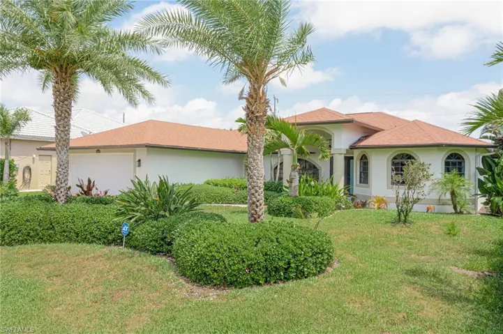 View of front of property with stucco siding, an attached garage, and a front lawn