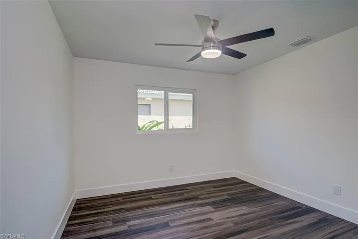 Unfurnished room with baseboards, ceiling fan, and dark wood-type flooring